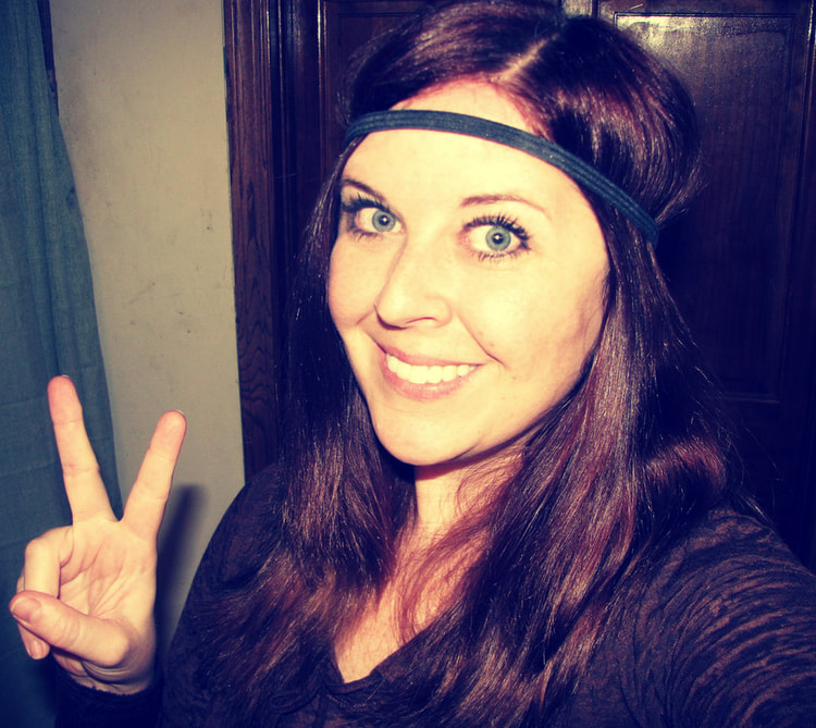 Female with brown hair with headband around forehead giving a peace sign.